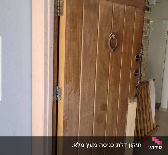 דלת עץ כבדה עם ידית מתכת עגולה